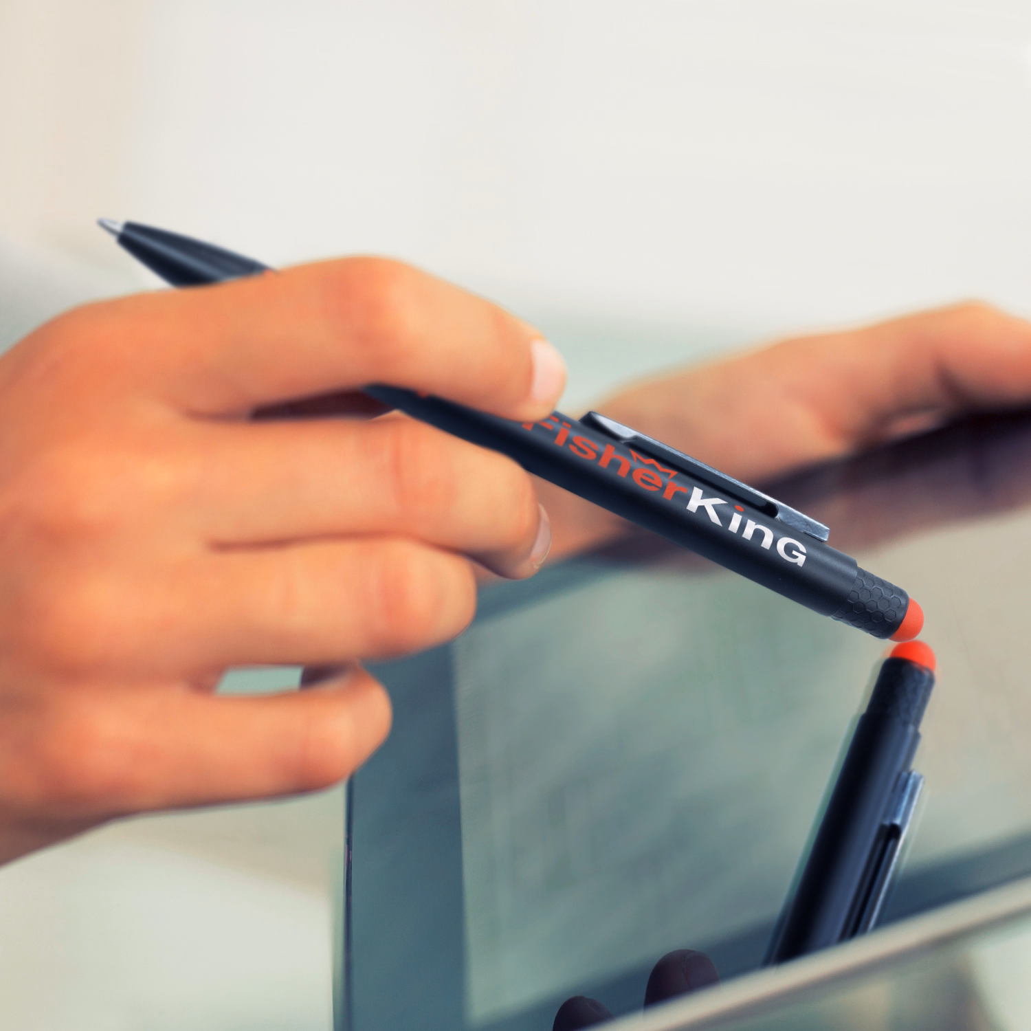 Hand using branded black stylus pen with red tip on touchscreen tablet