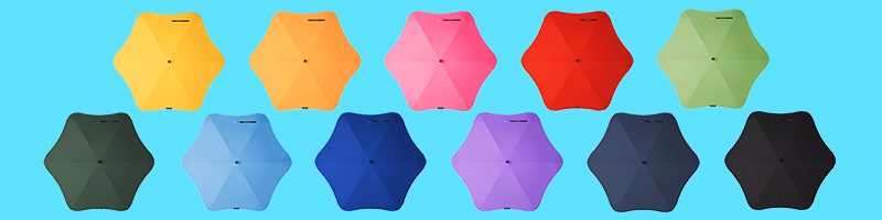 Assorted BLUNT umbrellas displayed top-down in multiple bright colours on blue background