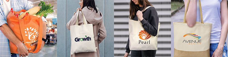 Hands holding and displaying assorted cotton tote bags in natural colours with printed logos used for shopping and everyday carry