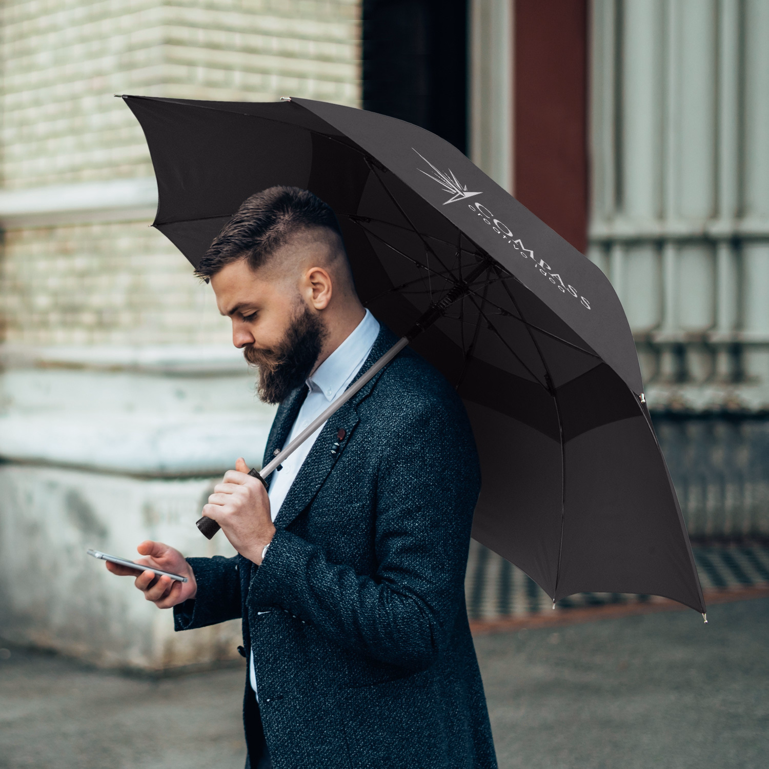 Person holding Hurricane Urban umbrella in black, open profile view with branded panel outdoors