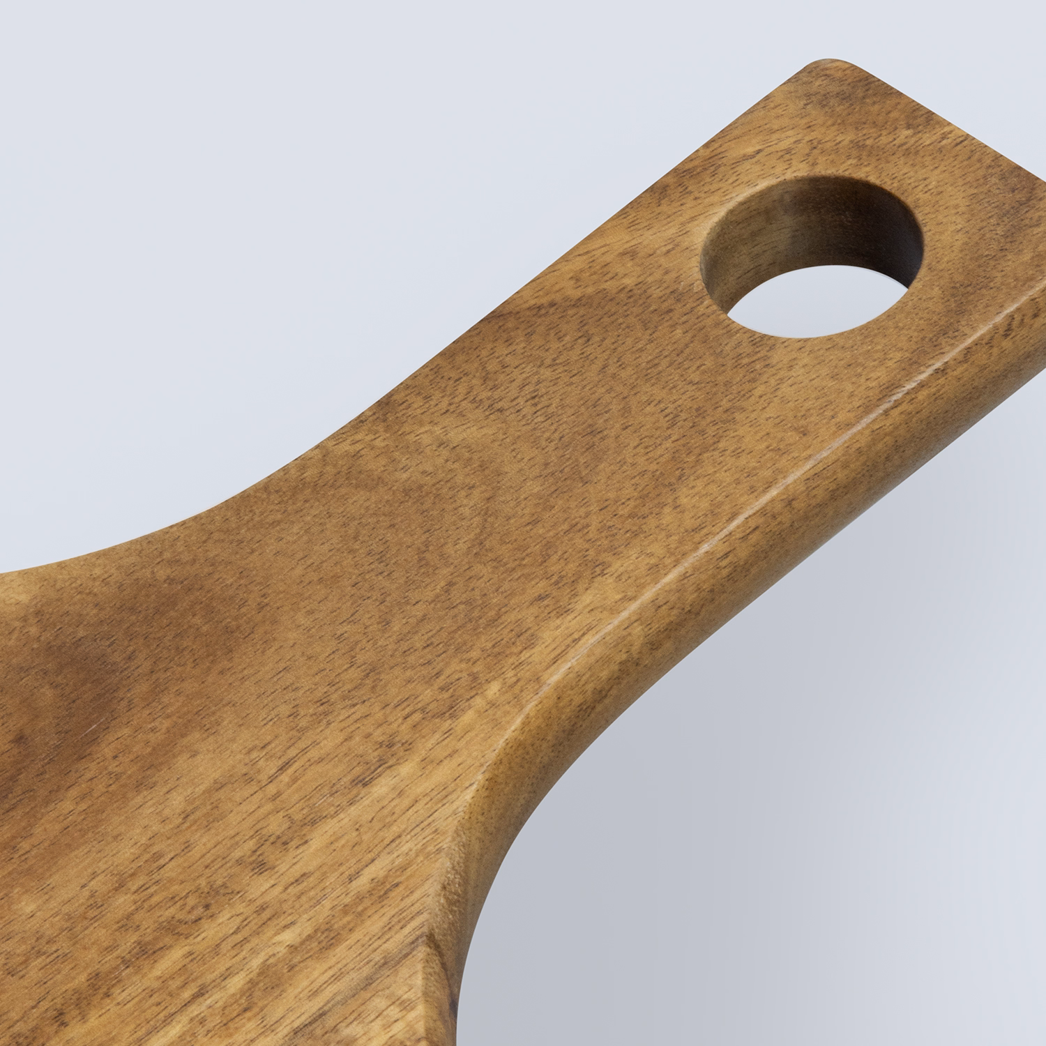 Close-up of acacia wood pizza board handle with smooth finish and hanging hole.