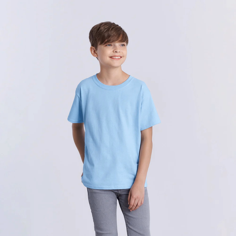 A smiling child wearing a light blue t-shirt and grey jeans, standing against a plain background, representing a comfortable and casual kids’ t-shirt style.