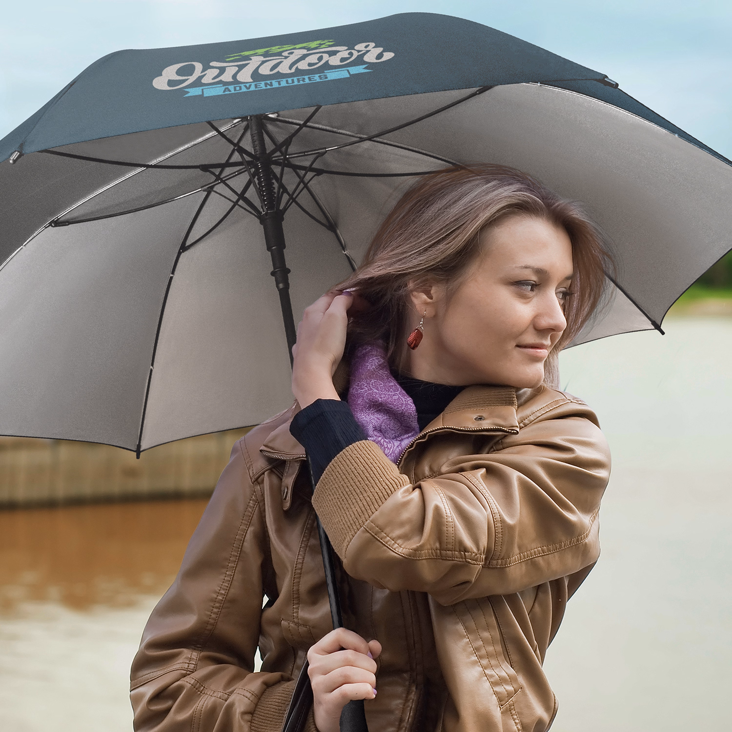 Person holding Patronus umbrella in navy and silver near lake on cloudy day