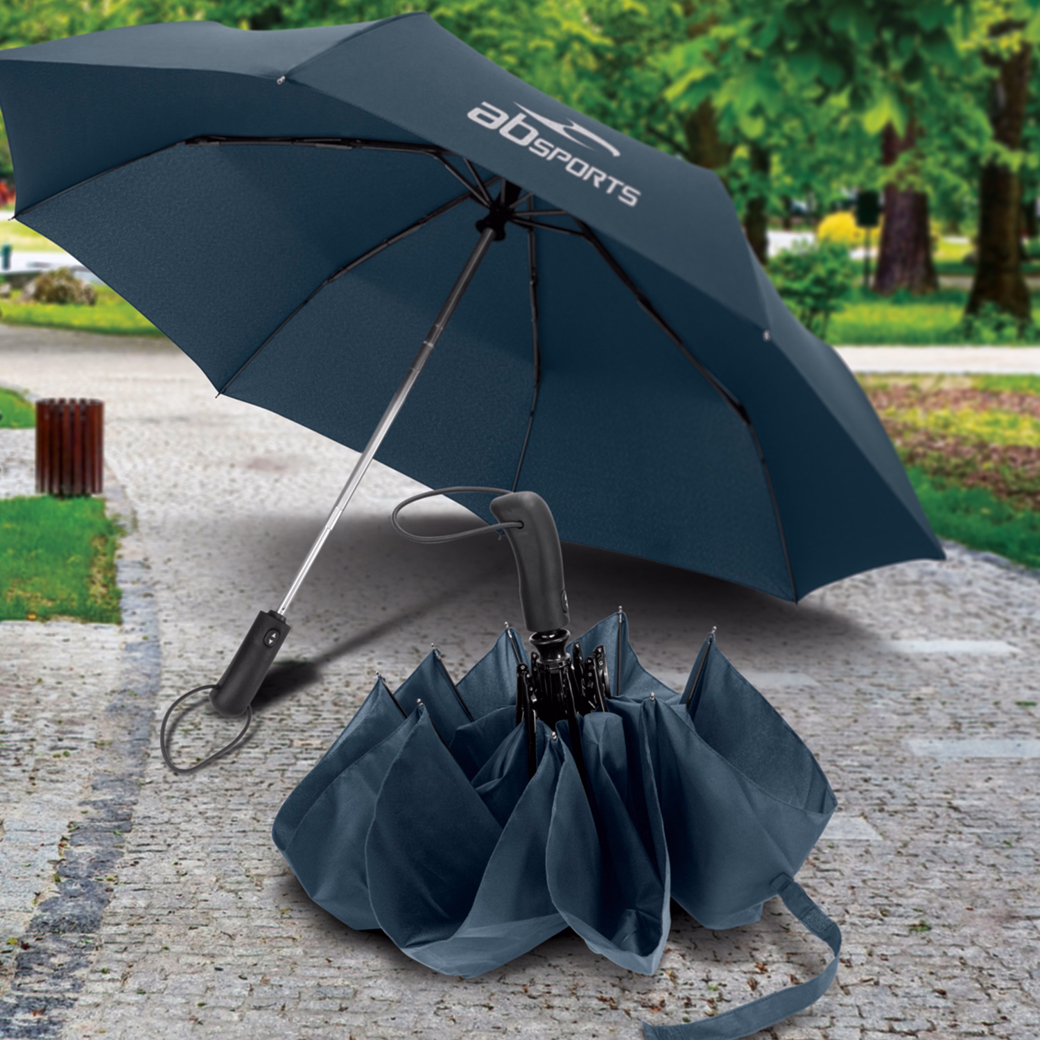 Open Prague Compact umbrella in navy with printed logo on pavement beside folded umbrella