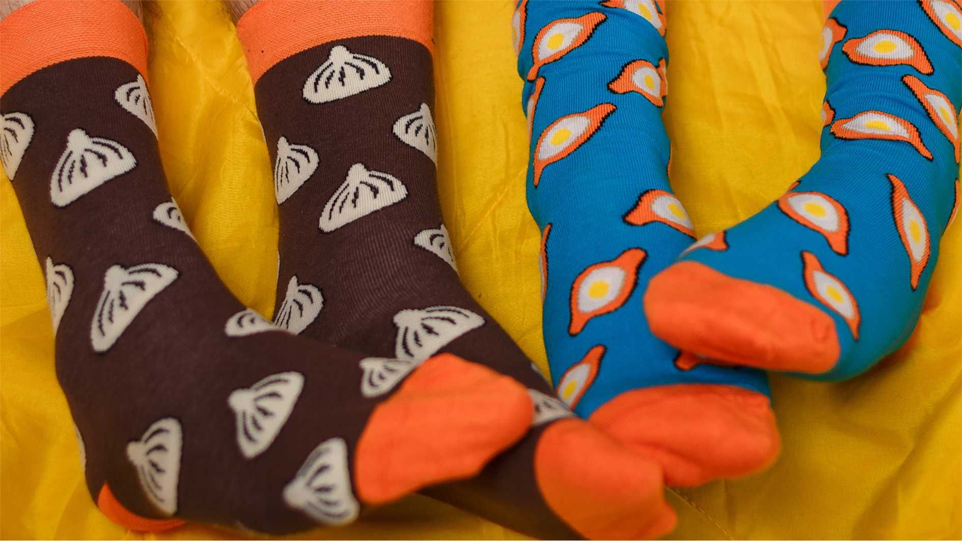 Colourful patterned socks with orange toes and cuffs on yellow background.